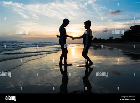 Silhouette of brothers holding hands on the beach Stock Photo - Alamy