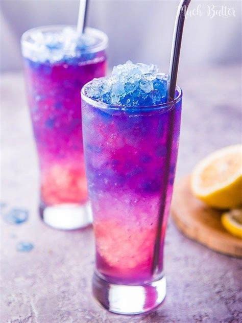 two glasses filled with purple and blue liquid next to lemon slices on a table top