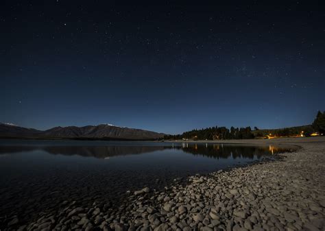 Lake Tekapo at night. Stars above the perfect smooth lake surface and ...
