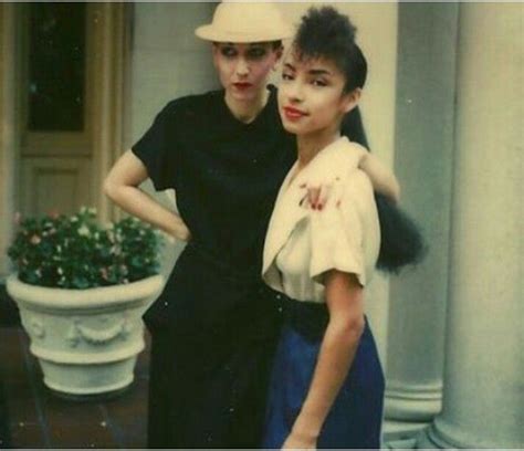 two women standing next to each other in front of a building with ...