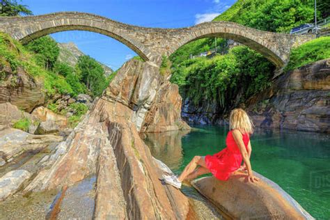 Woman sunbathing under Roman stone bridge: Ponte dei Salti over Verzasca River. Verzasca valley ...