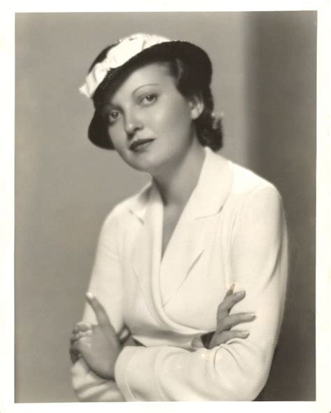 an old black and white photo of a woman in a suit with her arms crossed