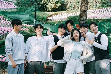 a group of young people standing next to each other in front of a flower garden