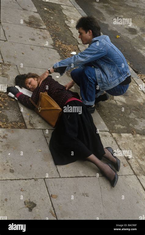 woman who has collapsed on the street being helped by a man Stock Photo ...