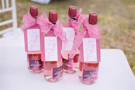 four pink bottles with labels on them are sitting on a white cloth covered tablecloth