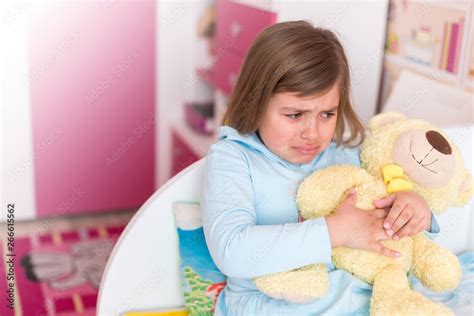 Cute adorable little girl crying in children's room hugging teddy bear ...