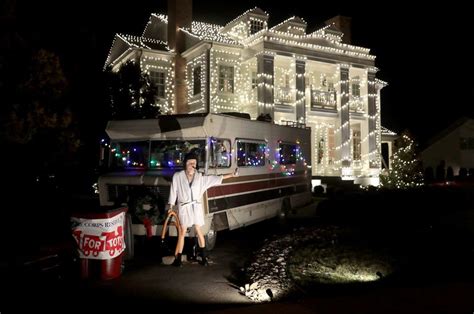 a man standing in front of a house covered in christmas lights