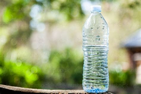 Image of Close up of plastic water bottle outside with green bokeh background - Austockphoto