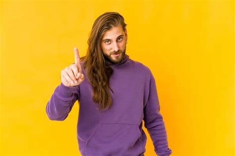Young Man Long Hair Look Smiling Cheerfully Pointing Forefinger Away Stock Photo by ...