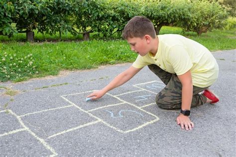 Premium Photo | The boy draws on the pavement with crayons in the park