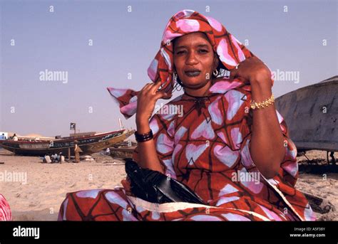 Mauritanian woman in colourful traditional clothing sitting on beach ...