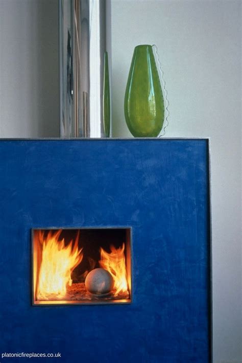 a blue fireplace with flames in it next to a green vase and other items ...