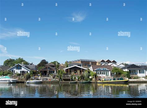 homes lining the river thames in thames ditton, surrey, england, seen from the opposite bank ...