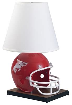 a lamp with a football helmet on it and a white shade is sitting next ...