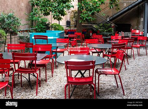 Bright red metal chairs around grey tables on a stone patio with trees and stairs Stock Photo ...