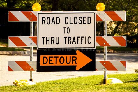 Road Closed To Thru Traffic Detour Sign on Striped Barrier with Reflectors on Side of Road on ...