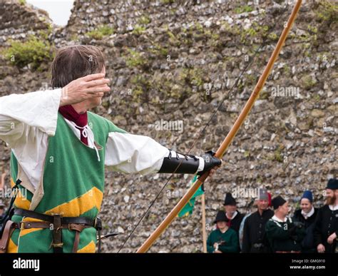 A medieval reenactor displays longbow archery techniques within the grounds of Portchester ...