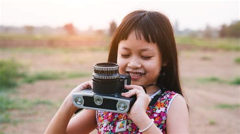 Little Child Girl Holding Medium Format Film Camera and Taking Photo of Sunset Landscape with ...