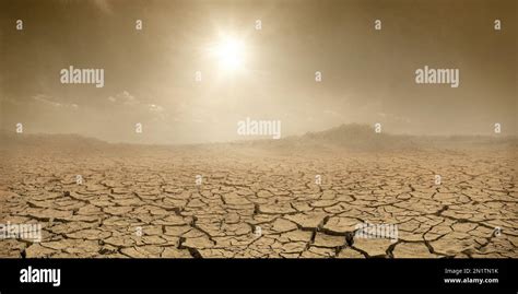 Barren terrain panorama, sun shining over cracked dried land and clouds of dust, climate change ...