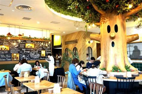 people sitting at tables in a restaurant with a tree growing on the wall behind them