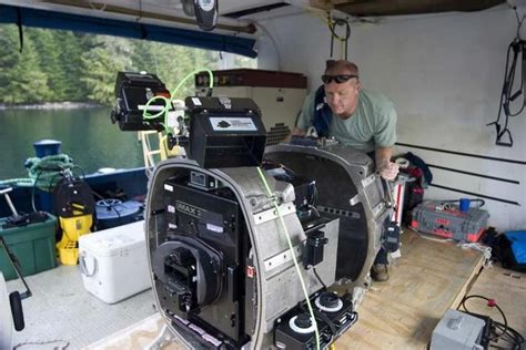 a man standing on top of a boat next to other boats in the water and equipment