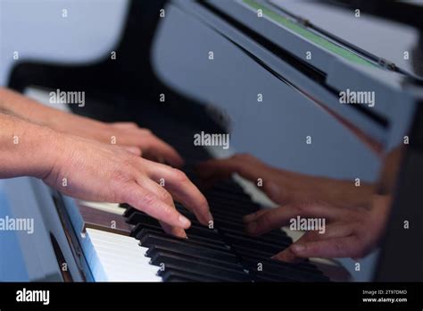 Human hands playing the keys notes and chords on a classic black piano ...