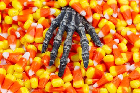 Scary hand in pile of candy corn | High-Quality Holiday Stock Photos ~ Creative Market