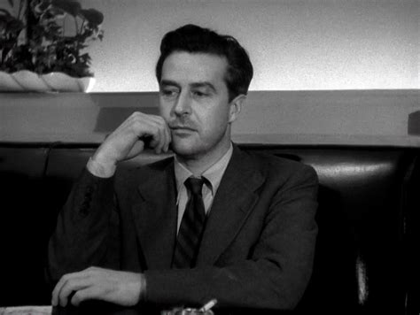 a man in a suit and tie sitting at a table with his hand on his chin