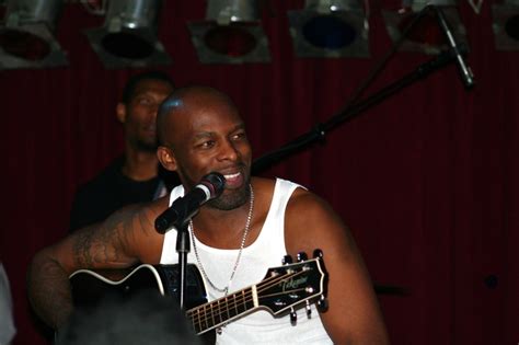 a man holding a guitar and singing into a microphone