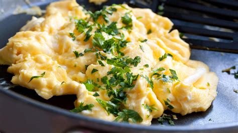 scrambled eggs with parsley on top in a frying pan