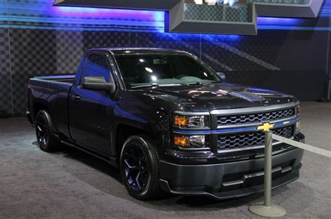 a black truck parked in front of a blue and white wall with lights on it