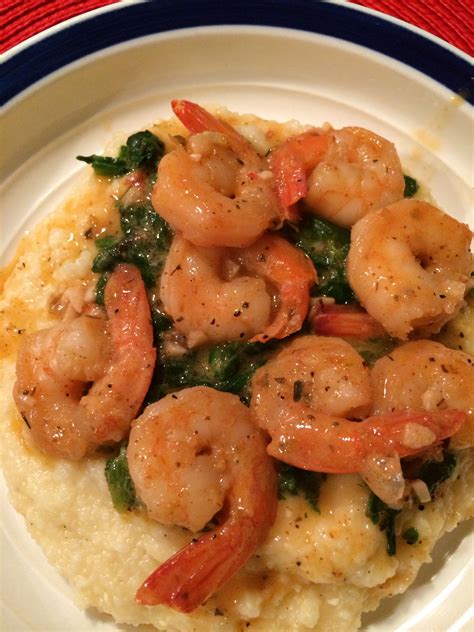 shrimp and spinach on top of grits on a white plate with blue trim