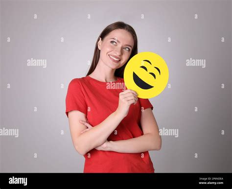 Happy young woman with laughing emoji on grey background Stock Photo - Alamy