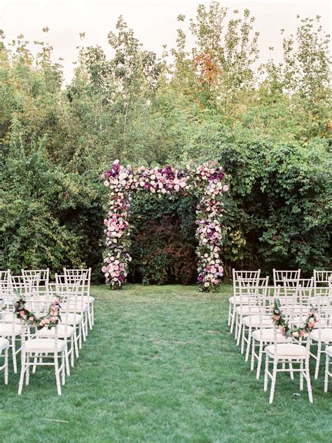Lovely trellis decorated with flowers and greenery for a backyard wedding ceremony. White ...