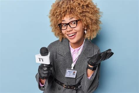 Premium Photo | Positive curly haired female tv presenter holds microphone prepares reportage ...