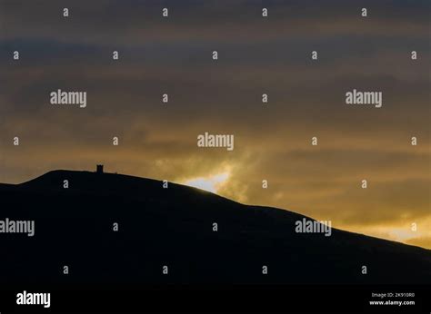 Autumn sunrise at Rivington Pike with hill in silhouette and sun ...