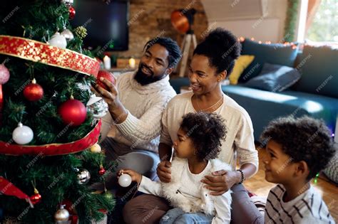 Premium Photo | Happy black family decorating Christmas tree in the ...