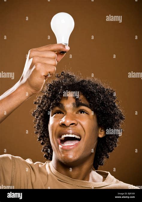 young man in a brown shirt holding light bulbs Stock Photo - Alamy