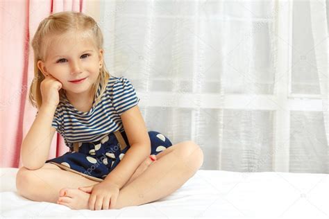 Adorable little girl sitting on the bed Stock Photo by ©photo_oles 81233478