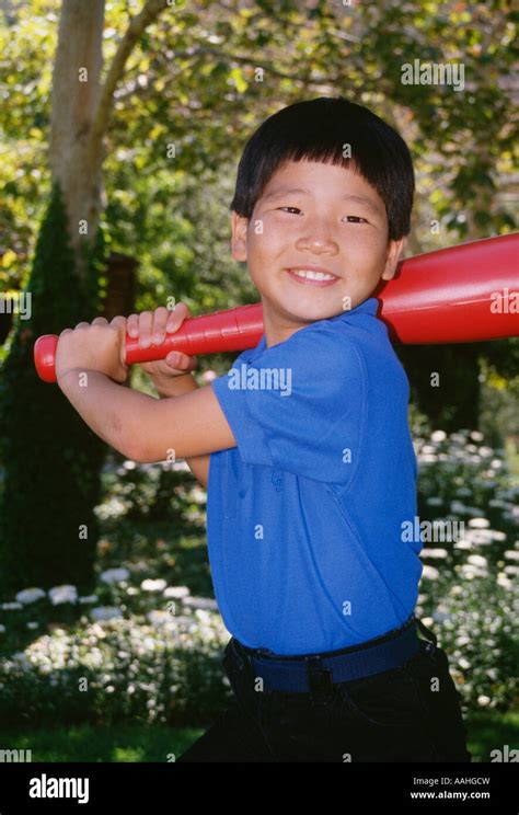 Portrait young Ethnic Korean Boy 4-5 year old holding large plastic toy baseball bat batting ...