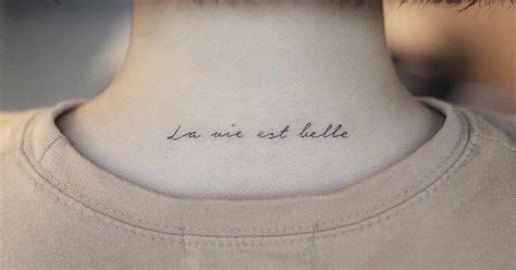 "La vie est belle" lettering tattoo on the upper back.