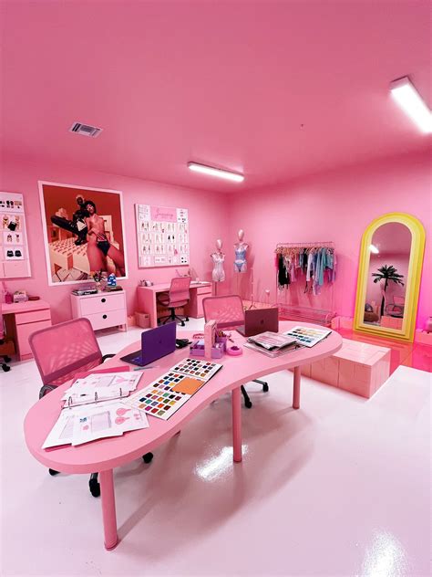 a room with pink furniture and pictures on the walls, including an office desk in front of a mirror