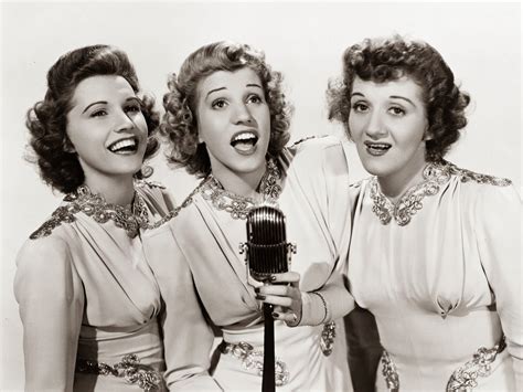 three women singing into a microphone with their mouths open
