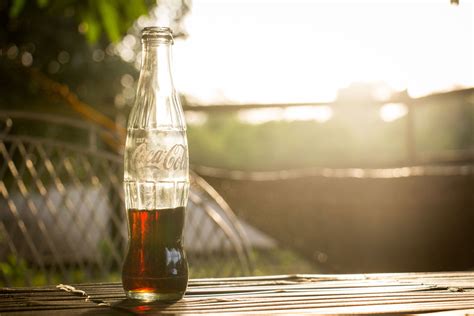 a glass bottle of coca cola on a table during golden hour, coca cola bottle 4k HD Wallpaper