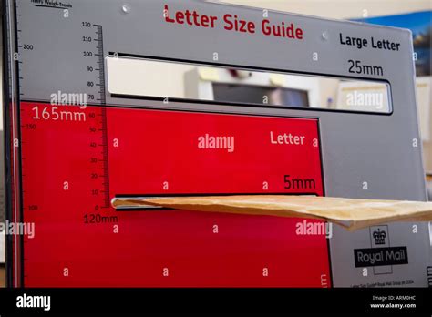 USING ROYAL MAIL LETTER SIZE GUIDE with brown envelope being measured Stock Photo: 9189403 - Alamy