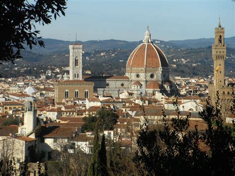 the city is surrounded by tall buildings and hills in the distance, with trees on either side