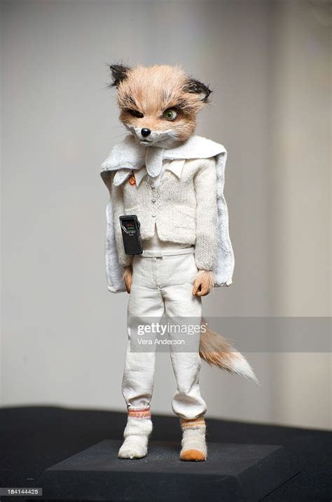 a toy fox wearing white clothes and holding a cell phone