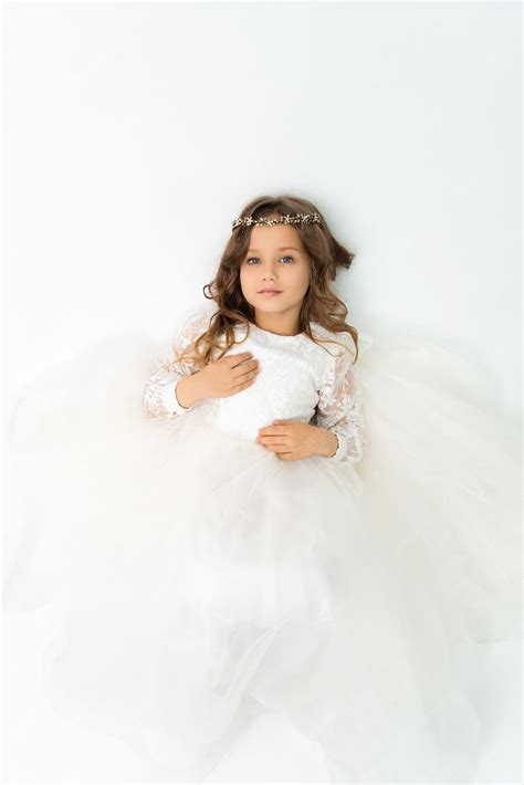 Premium Photo | A little girl lying in a white dress and looking at the camera studio portrait