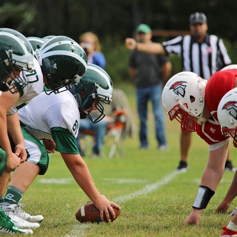 a group of young football players standing on top of a field next to each other