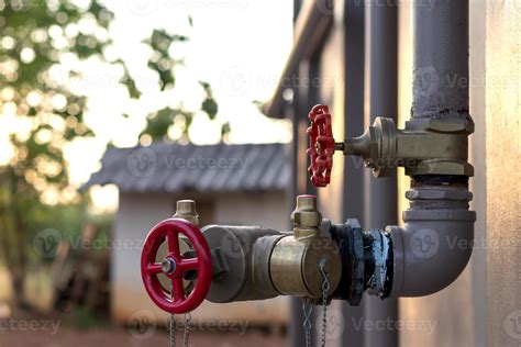 Red valve with steel pipe near the wall. 7554881 Stock Photo at Vecteezy